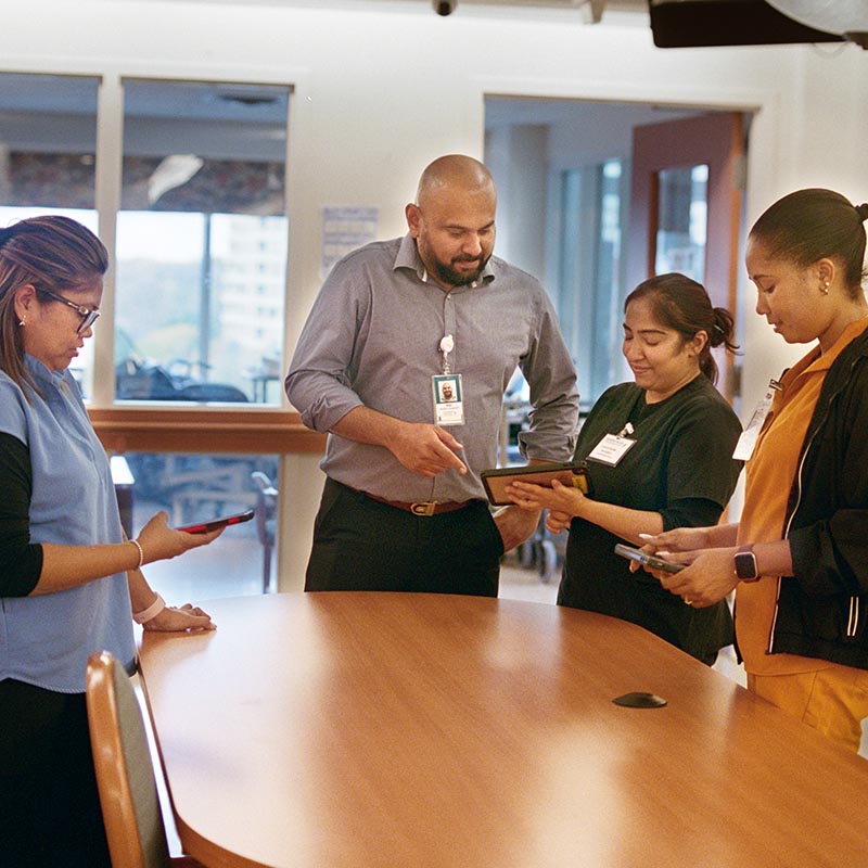 A group of four LTC staff look at a tablet