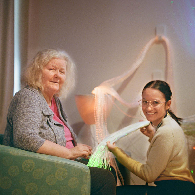 A care worker shows a string of LED lights to a senior woman