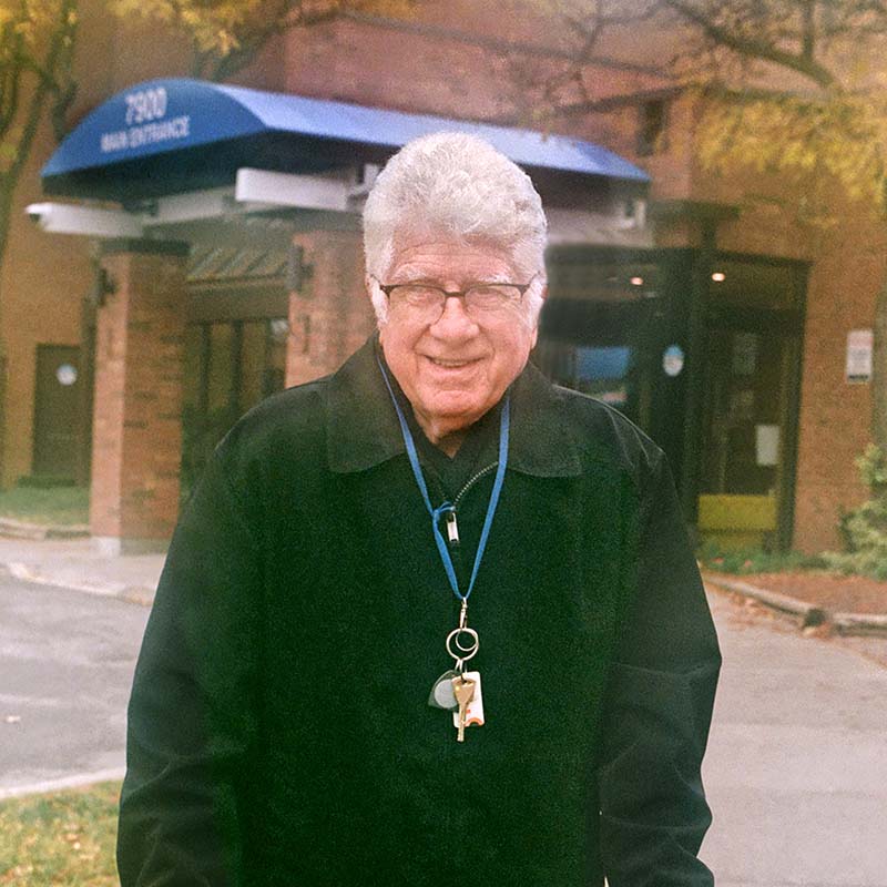 A senior man stands in front of a care home